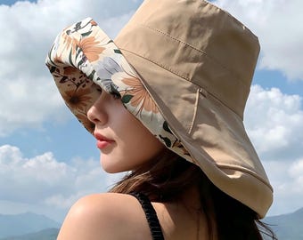 May include: A beige sun hat with a wide brim. The underside of the brim has a floral pattern with orange and cream flowers. The hat is designed for sun protection and is suitable for outdoor activities.