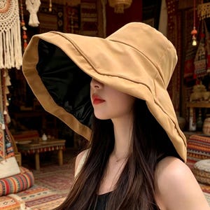 Puede incluir: Un sombrero de sol beige con ala ancha y forro interior negro. El sombrero tiene un dise&ntilde;o estructurado con ala ligeramente curvada. El sombrero est&aacute; hecho de un material suave y es adecuado para la protecci&oacute;n solar. Es un accesorio de moda.