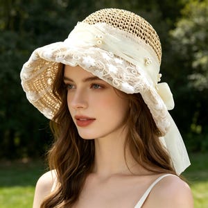 Peut inclure: Chapeau de soleil en paille avec un large bord, orné de dentelle ivoire et d'un ruban crème. Le chapeau présente de délicats accents de perles et un nœud à l'arrière, un accessoire élégant pour se protéger du soleil.