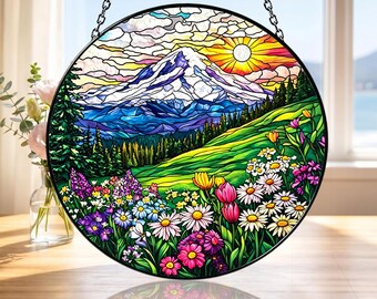 Könnte beinhalten: Runde Glasmalerei mit einer Berglandschaft mit schneebedecktem Gipfel, strahlender Sonne und einem Feld bunter Wildblumen. Die Tafel ist schwarz gerahmt und hängt an einer Kette.