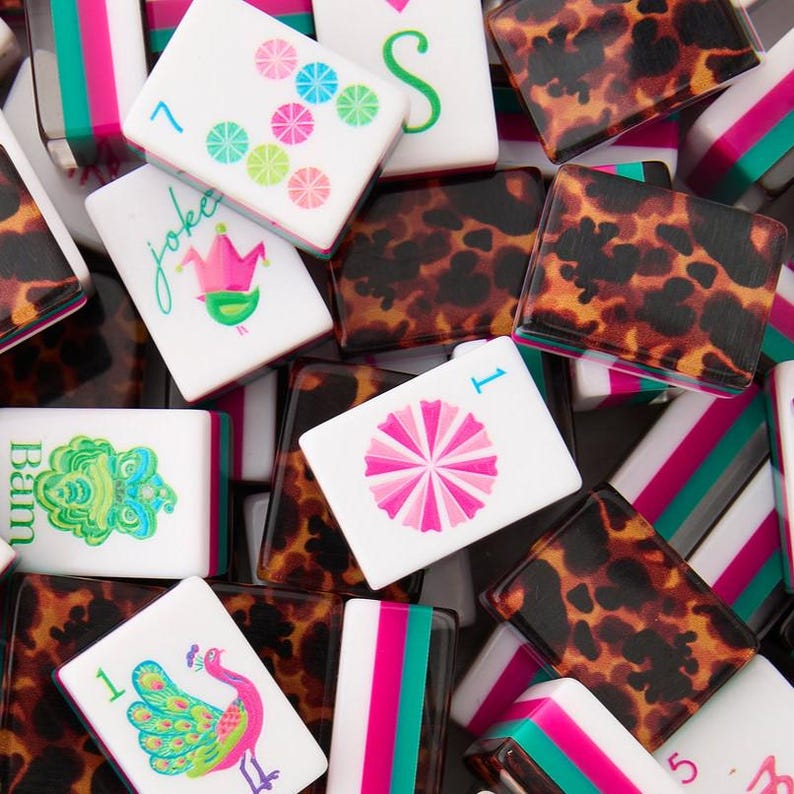 May include: A collection of rectangular mahjong tiles featuring white faces with colorful illustrations including a pink peacock, a green dragon, a pink flower, and a joker crown. The backs and sides display a brown and black leopard print pattern.