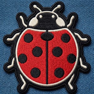 May include: An embroidered patch featuring a ladybug with a bright red wing cover, black circular spots, and a black head. The insect has white accents on its head and legs, with a thick black border outlining the entire shape of the ladybug.