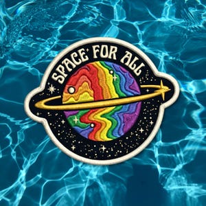 May include: Embroidered patch featuring a colorful planet with a rainbow design and a gold ring. The patch has the text "SPACE FOR ALL" in white lettering and is set against a black background with stars. The patch is bordered with a white outline.