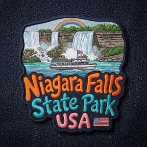 May include: An embroidered patch featuring a scenic view of Niagara Falls with a tour boat in the water, a rainbow in the sky, and the text Niagara Falls State Park USA with a small American flag icon, all outlined in dark blue thread.