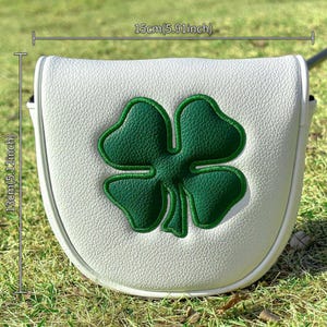 May include: A white mallet putter headcover featuring a large green four-leaf clover embroidery. The cover measures 5.91 inches in width and 5.12 inches in height. The textured white material contrasts with the bold green clover design.