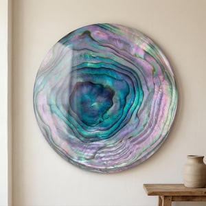 May include: A circular wall art piece featuring a polished abalone shell surface with concentric, swirling patterns in vibrant shades of deep blue, teal, turquoise, and iridescent lavender, creating a natural, multi-layered, glossy finish.