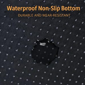 Pu&ograve; includere: Primo piano di un tessuto nero, strutturato, con una superficie antiscivolo. Il tessuto presenta piccoli punti bianchi in rilievo e una macchia d'acqua scura. Il testo in arancione recita "Waterproof Non-Slip Bottom" e "Durable and Wear-Resistant."