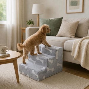 May include: A three-step pet stair in light gray with a white bone pattern. A small, light brown dog stands on the top step near a beige sofa. The stairs are designed to help pets reach furniture.