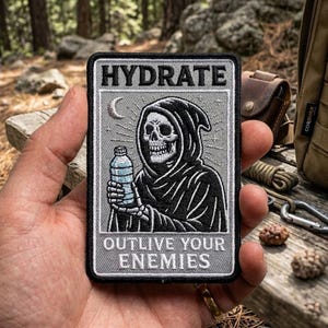 May include: Embroidered patch with the words "HYDRATE" and "OUTLIVE YOUR ENEMIES". The patch features a grim reaper holding a water bottle, with a crescent moon in the background. The patch is gray, black, and white.