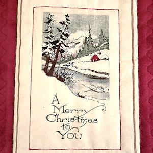 May include: A rectangular fabric panel with a Christmas theme, depicting a winter landscape. The image shows snow-covered trees, a river, and a small red house. The text "A Merry Christmas to You" is printed below the scene.