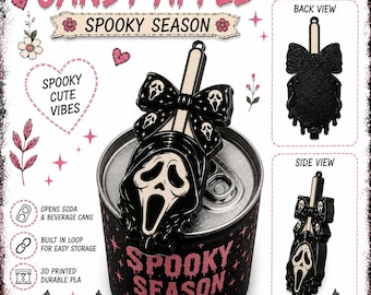 May include: A black and cream-colored plastic can opener shaped like a ghost mask with a bow, featuring a built-in loop for storage. The design includes a ghost face pattern on the bow and a larger ghost face on the main body, shown in use on a soda can.