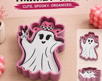 May include: A pink trinket tray shaped like a ghost wearing a pink cowgirl hat with a checkered band. The ghost has black eyes, a heart-shaped nose, and is making a peace sign. Text reads: SPOOKY COWGIRL GHOST TRINKET TRAY, CUTE. SPOOKY. ORGANIZED.