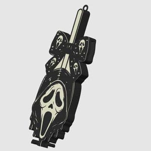 May include: A black and off-white decorative accessory featuring a central ghost-like mask graphic with a long, flowing hood. The design includes a bow element adorned with smaller mask icons and tiny star shapes, finished with a small loop at the top.