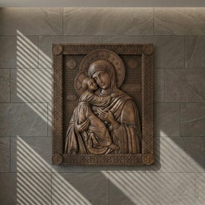Puede incluir: Un detallado relieve marrón de la Virgen María sosteniendo al niño Jesús. La obra de arte está enmarcada con bordes ornamentados y está montada en una pared de azulejos grises. La talla está iluminada por luz natural.
