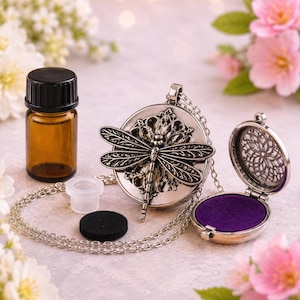 Peut inclure: Un collier médaillon en métal argenté avec un motif de libellule sur le devant, accompagné d'un petit flacon en verre ambré avec un bouchon noir, un insert en plastique transparent, un tampon en feutre noir et un médaillon ouvert avec un tampon violet.