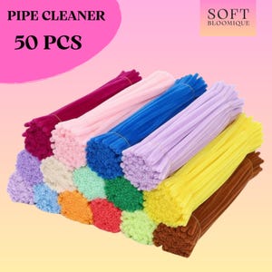 May include: A selection of colourful pipe cleaners in shades of pink, blue, purple, and yellow. The image displays a collection of 50 pieces, ideal for craft projects. The text "PIPE CLEANER 50 PCS" is visible at the top.