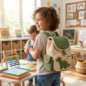 May include: A crochet backpack featuring a cream-colored main body with a green flap, green side pockets, and a green dinosaur appliqué with a speech bubble containing the text ROAR. The bag has wooden button closures and a green tassel.