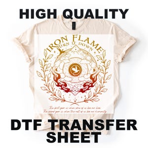May include: A cream-colored t-shirt with a DTF transfer sheet design. The design features the text "IRON FLAME BURN IT DOWN" in a circular pattern with a central emblem and flame accents. The shirt also has the text "HIGH QUALITY" and "DTF TRANSFER SHEET".