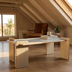 May include: A rectangular coffee table constructed from light-colored wood with a smooth, flat top surface and four vertical panel legs that slot into the tabletop edges. The table features a clean, light-toned finish and a simple, functional design.