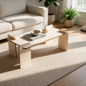 May include: A light-colored wooden coffee table with a rectangular top and two vertical slab legs. The table features a smooth, flat surface and a clean, structural design. It is positioned in a room with a light-colored sofa and a textured rug.