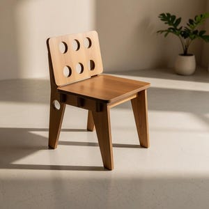 May include: A light brown wooden chair featuring a square seat and a backrest with six circular cutouts arranged in two rows of three. The chair has four angled legs, with a single circular cutout visible on the front left leg support structure.