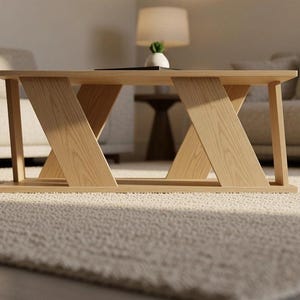 May include: A light-colored wooden coffee table featuring a rectangular top and a base constructed with two angled, Z-shaped support legs on each side. The table has a smooth, natural wood grain finish and a clean, geometric structural design.