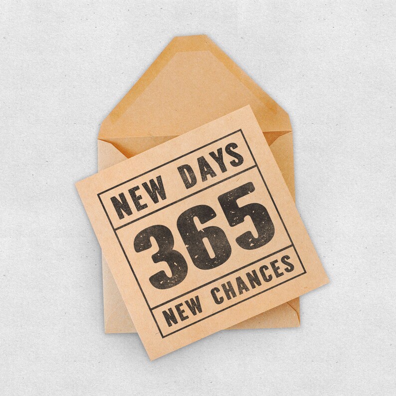 May include: A brown envelope with a card inside. The card is brown with black text that reads "NEW DAYS 365 NEW CHANCES".