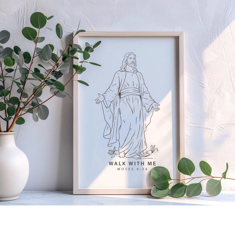 May include: A framed print featuring a line drawing of a figure with outstretched arms. The artwork is in black and white, with the text "WALK WITH ME MOSES 6:34" at the bottom. The frame is light-colored wood. A vase with greenery is to the left.