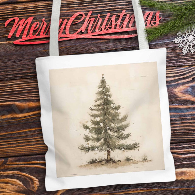 K&ouml;nnte beinhalten: Eine wei&szlig;e Einkaufstasche mit einer Aquarell-Illustration eines gr&uuml;nen Weihnachtsbaums mit wei&szlig;en Ornamenten auf beigefarbenem Hintergrund.