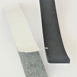 May include: Two pieces of black foam tape with adhesive backing. One piece has the white backing partially peeled away, revealing the grey adhesive. The other piece is solid black.