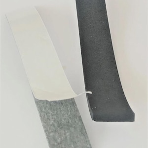 May include: Two pieces of black rubber stripping with adhesive backing. One strip is peeled back, revealing the grey adhesive. The other strip is solid black. The background is white.