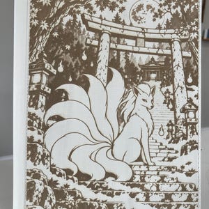 May include: A white rectangular binder featuring a brown ink illustration of a nine-tailed fox sitting on stone steps. The scene includes a torii gate, a full moon, stone lanterns, and maple trees. The design covers the front cover of the binder.