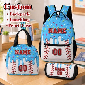 May include: A custom backpack, lunchbag, and pencil case set featuring a white baseball pattern with red stitching and a blue icing drip design with colorful sprinkles. Each item displays the red text NAME and the number 00 in a bold font.