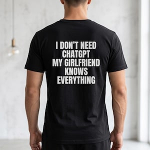Peut inclure: T-shirt noir avec texte blanc au dos : "I DON'T NEED CHATGPT MY GIRLFRIEND KNOWS EVERYTHING." Le t-shirt à manches courtes est en matière souple. Le texte est en gras, en police sans-serif.