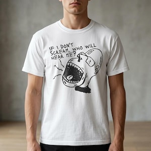 以下が含まれることがあります： 白いTシャツ。黒と白の叫び顔のグラフィックと「IF I DON'T SCREAM, WHO WILL HEAR ME？」のテキスト。大胆な漫画風イラストのデザインです。
