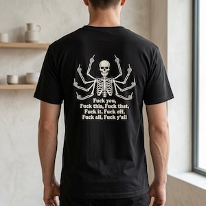 May include: A black short-sleeved t-shirt featuring a white graphic of a multi-armed skeleton giving the middle finger with each hand. Below the skeleton, the text reads: Fuck you, Fuck this, Fuck that, Fuck it, Fuck off, Fuck all, Fuck y'all.