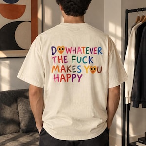 Peut inclure: Un t-shirt à manches courtes blanc cassé avec un texte coloré au dos qui dit : DO WHATEVER THE FUCK MAKES YOU HAPPY. Les lettres sont de différentes couleurs et la lettre O dans les mots DO et YOU est remplacée par un cœur jaune.