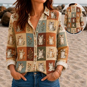 Puede incluir: Una camisa de manga larga con botones y un patrón de cuadrícula tipo patchwork de gatos ilustrados y flores en tonos tierra. El diseño incluye un cuello, una tapeta de botones frontal y un motivo repetitivo de varios gatos sentados.