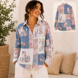 May include: A long-sleeved button-down shirt featuring a patchwork design with blue, pink, and white panels. The pattern includes illustrations of cats and floral motifs. The shirt has a collar and a front button closure, with a matching back view shown.