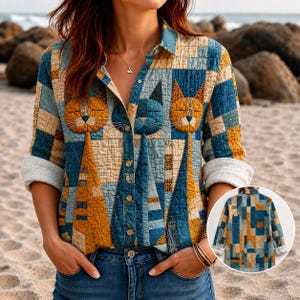 Könnte beinhalten: Ein langärmeliges Hemd mit Knopfleiste und gestepptem Patchwork-Muster in Blau-, Gelb- und Cremetönen. Das Design integriert stilisierte Katzengesichter und -körper in die geometrischen Blöcke. Ein kleiner Einschub zeigt die Rückansicht.