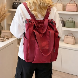 May include: A white ceramic mug with a black handle and the text "But First, Coffee" in a bold, black font. The mug is set against a blurred background, suggesting a cozy setting.