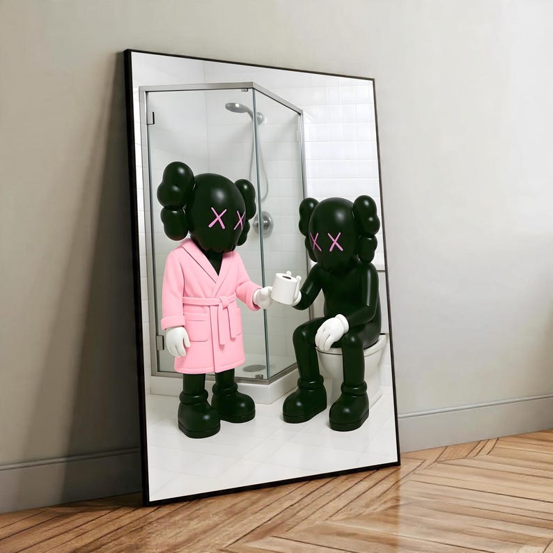 May include: A framed artwork featuring two dark green figures with pink 'XX' eyes. One figure wears a pink robe and holds a roll of toilet paper, offering it to the other figure seated on a toilet. The artwork is set in a bathroom scene.