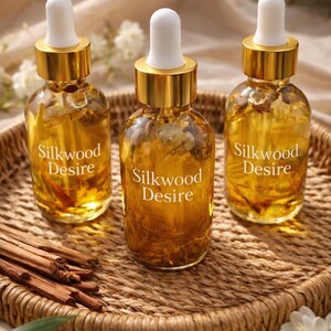 May include: Three glass bottles with gold lids and white droppers, filled with a golden liquid. The bottles are labelled "Silkwood Desire" and sit on a woven tray with cinnamon sticks. The background is a soft, neutral colour.