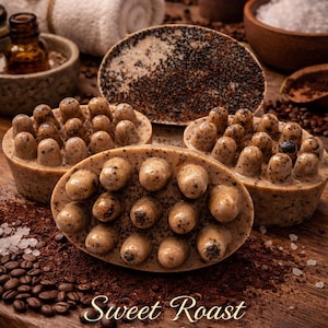 Op de afbeelding: Ovale mocha sculpt bars met een textuur, omringd door koffiebonen en -gruis. De bars zijn lichtbruin met donkerbruine accenten. De afbeelding bevat de tekst "Sweet Roast Mocha Sculpt Bar Exfoliating Coffee Massage Bar."