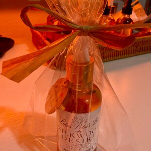 May include: A glass bottle with a gold cap and dropper, wrapped in cellophane and tied with a raffia bow. The label reads "Silkwood Desire" and "Pheromone Infused". A small tag says "Handmade with love".