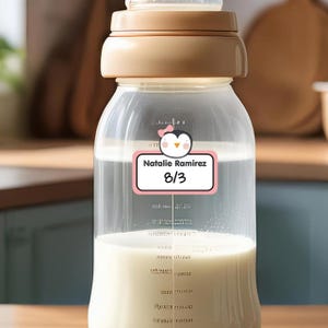 Peut inclure: Un biberon transparent avec un autocollant de pingouin rose et blanc qui dit "Natalie Ramirez 8/3".