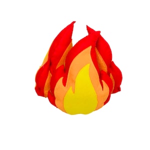 May include: A plush toy shaped like a flame, featuring layered fabric sections in vibrant shades of red, orange, and yellow. The soft, stuffed construction creates a three-dimensional fire effect with pointed, upright peaks and a rounded base.