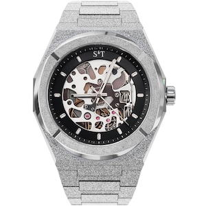 May include: Silver-toned skeleton watch with a textured finish. The watch features a black dial with visible internal mechanisms, pink jewels, and the letters "S&T" at the top. The watch band is also silver and textured.