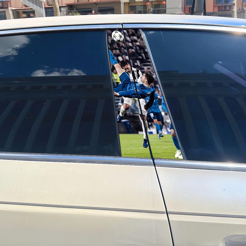 May include: Car window decals featuring a soccer player in a blue uniform performing a bicycle kick, with a soccer ball in the air. The background shows a stadium filled with spectators. The decals are applied to a white car.