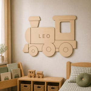 May include: A light-colored wooden wall decoration shaped like a steam locomotive train. The train features a chimney, a cabin with a square window, and three wheels. The name LEO is engraved in capital letters on the side of the train engine.